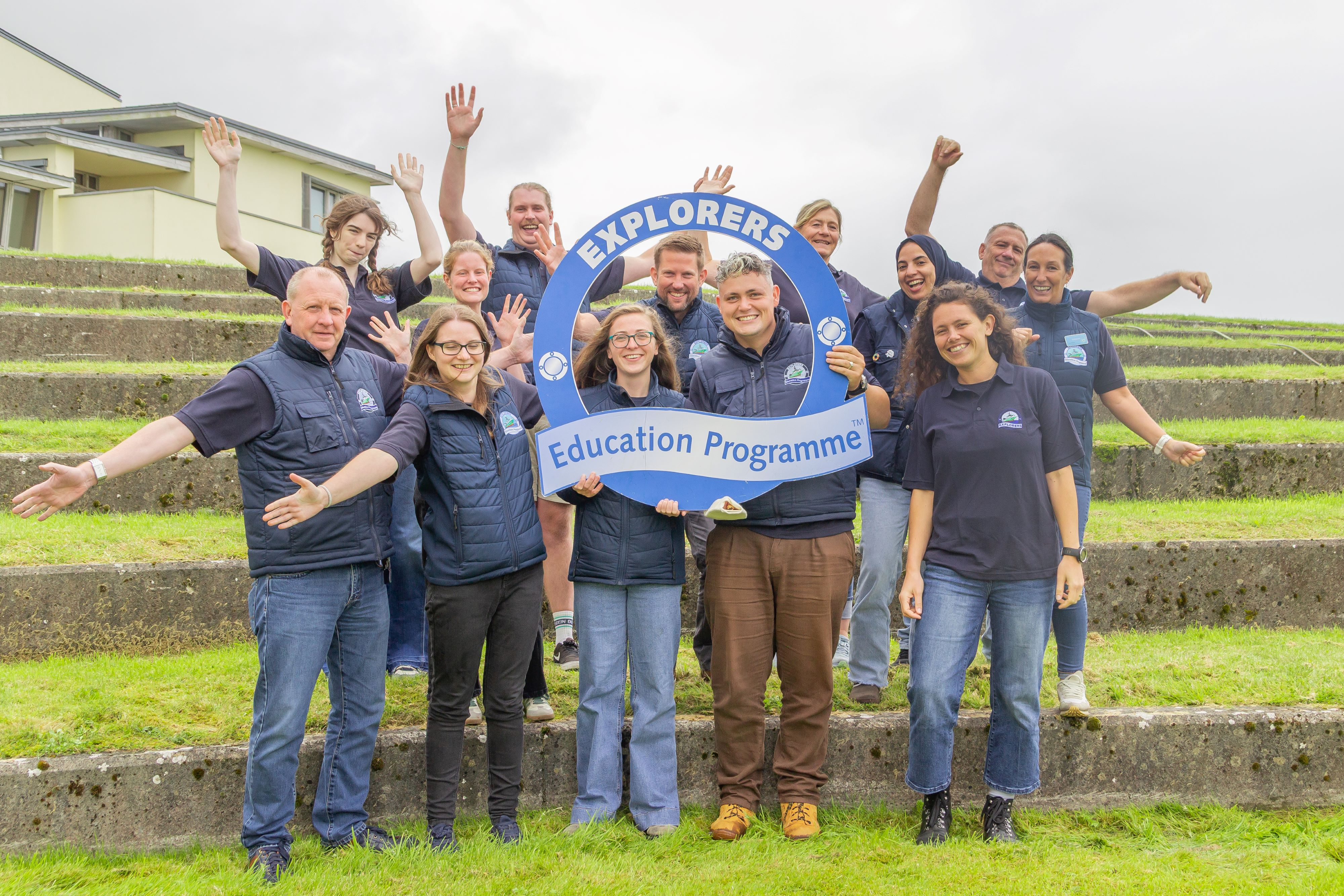 Explorers Education Programme team holding a blue programme sign