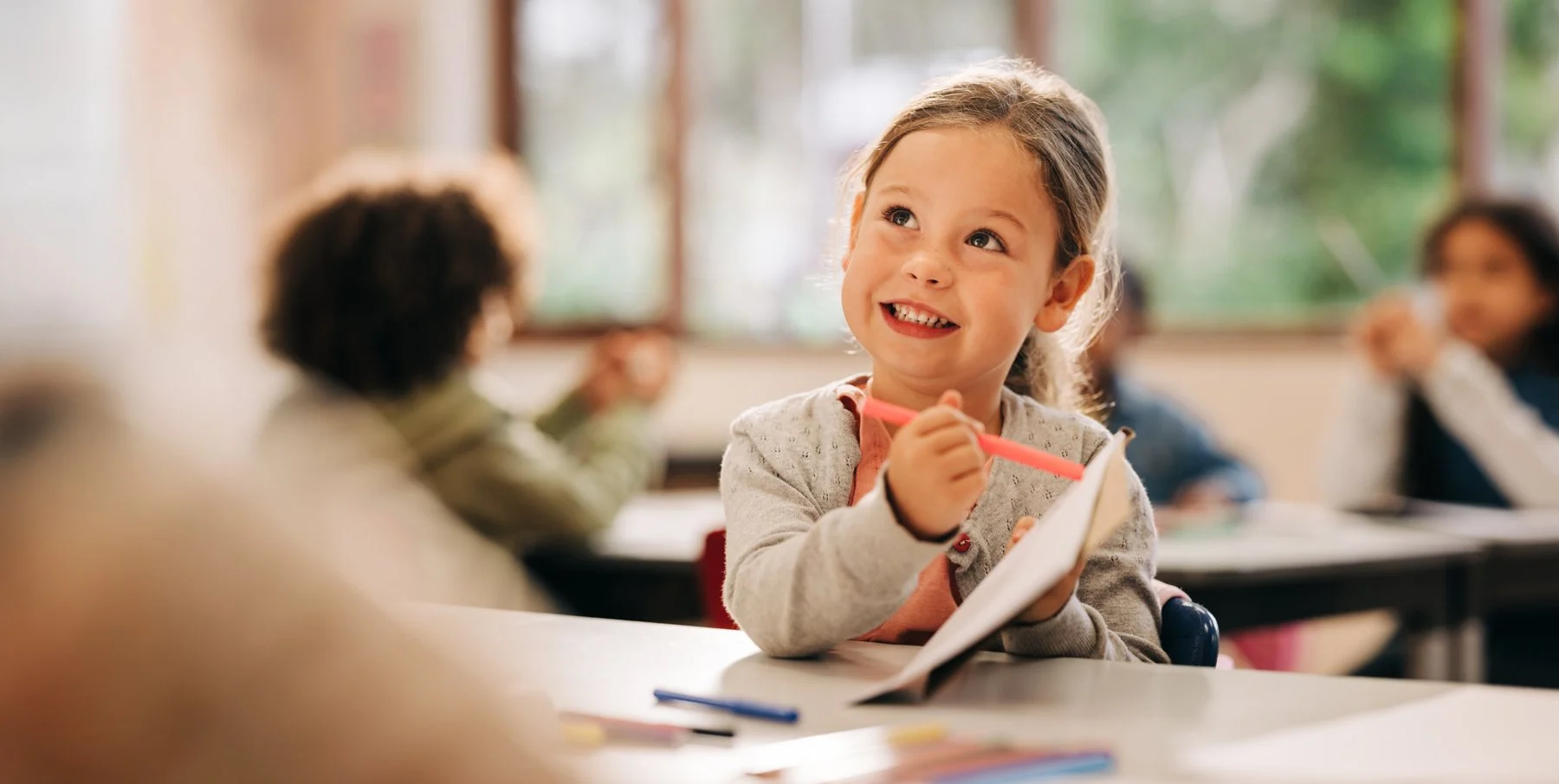 Child smiling in a classroom during a learning activity