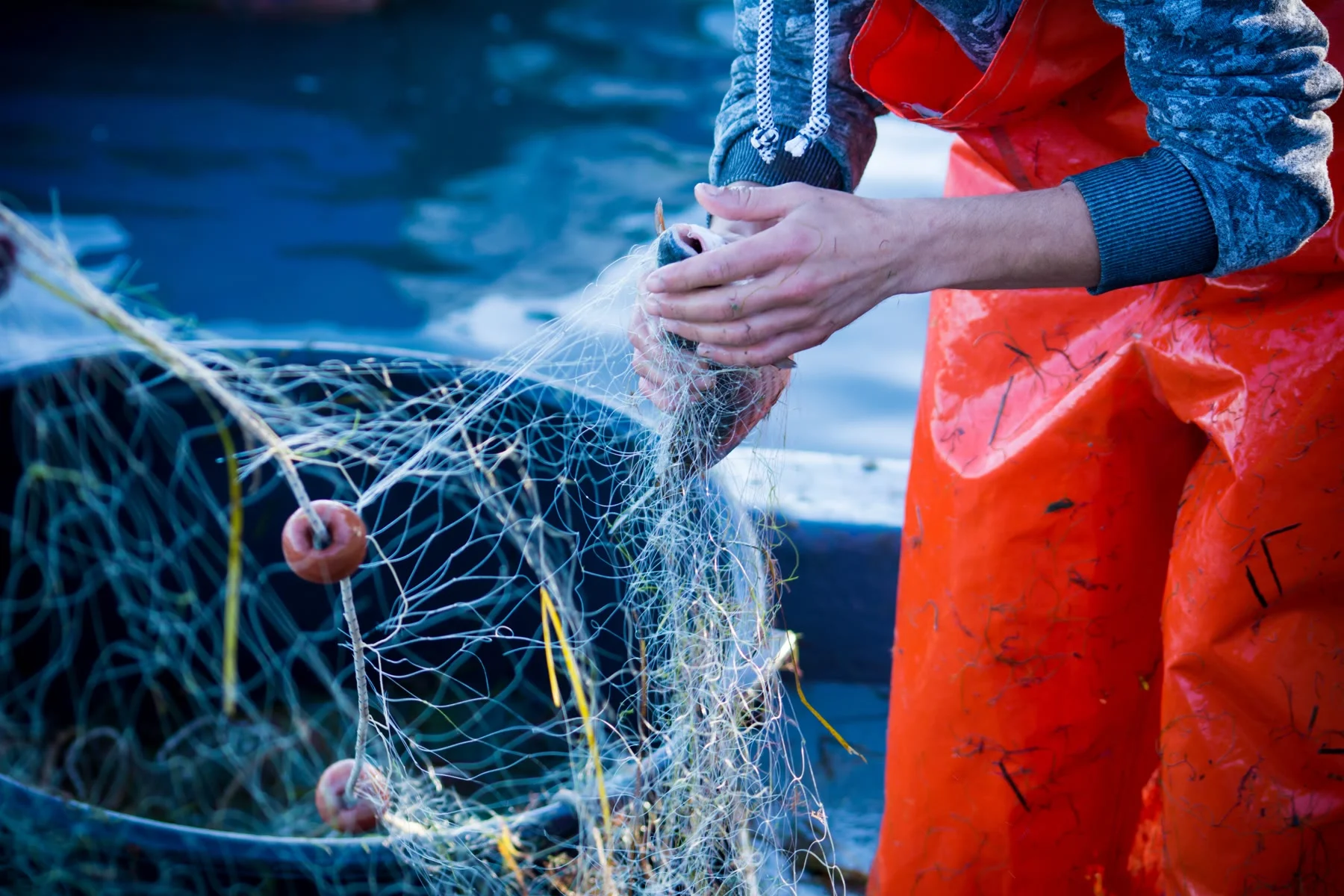 Person in orange waterproof clothing handling marine sampling equipment
