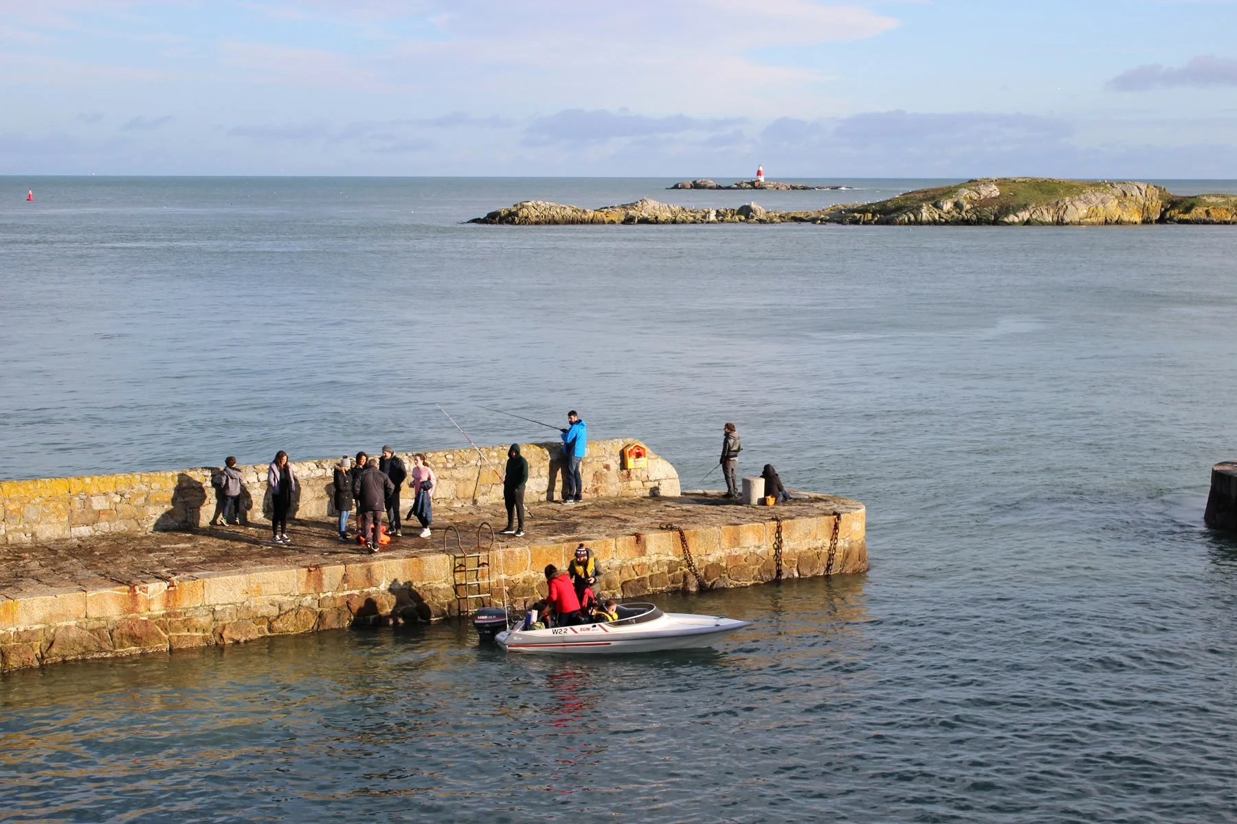 People standing on a pier beside coastal water