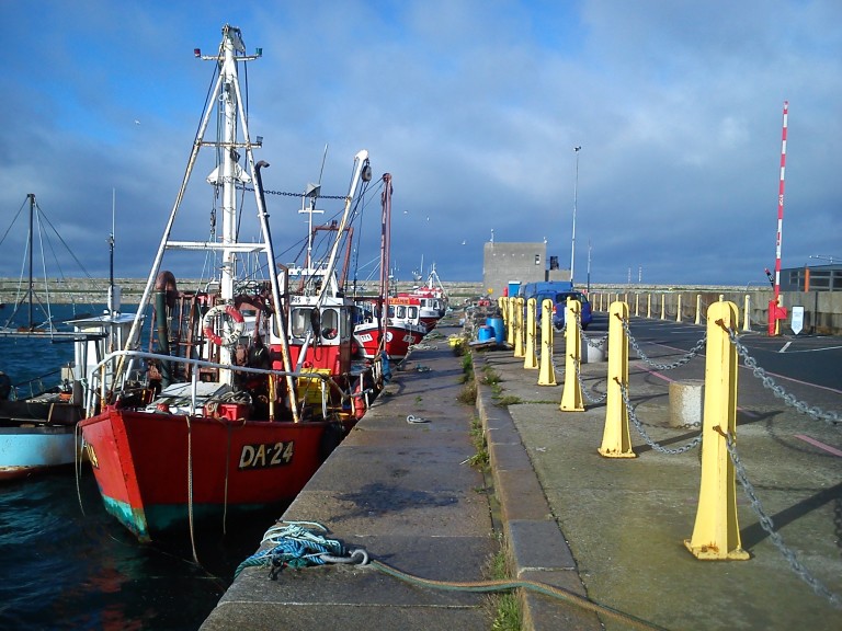 Red fishing vessels moored along a harbour quay.