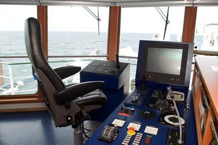 Research vessel bridge control station with a captain’s chair, screens and navigation controls.