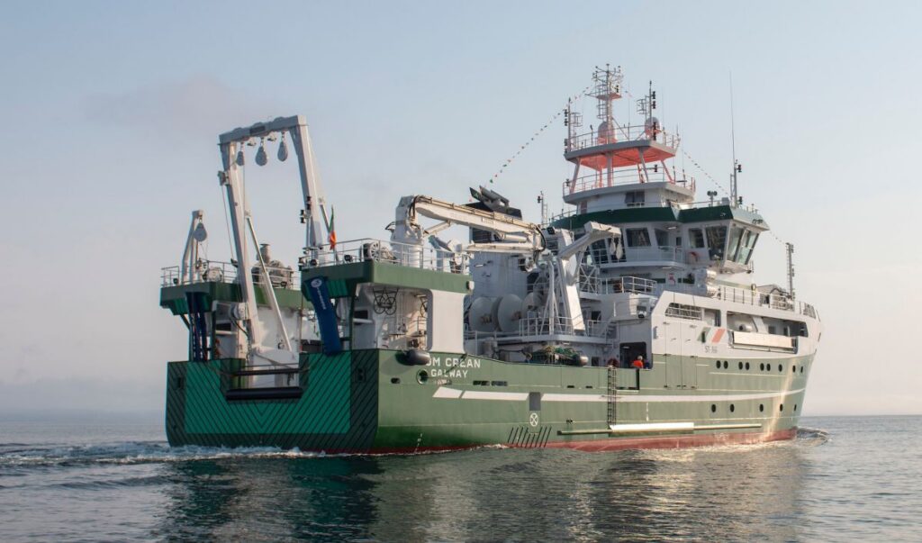 RV Tom Crean research vessel sailing at sea, viewed from the stern.