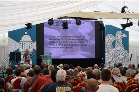 Speaker presenting to a seated audience at a conference.