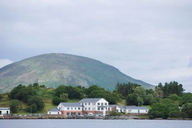 Newport Catchment Facilities beside the water, with trees and a mountain behind them